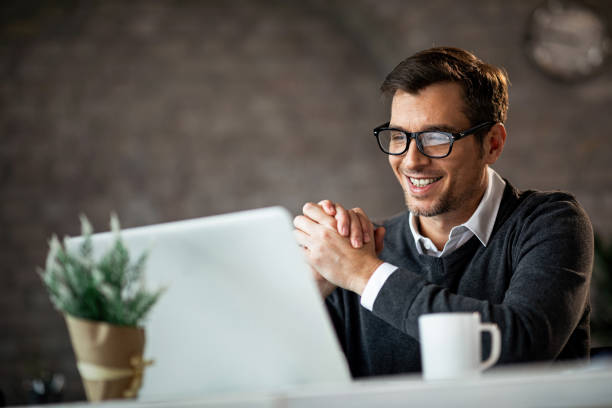 glückliche männliche unternehmer mit laptop während der arbeit im büro. - einzelner mann über 30 stock-fotos und bilder