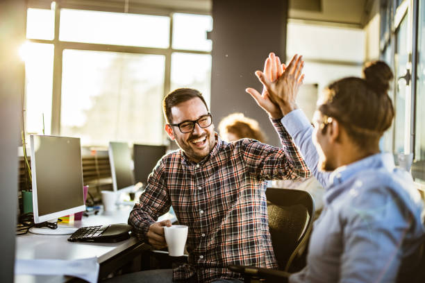 gelukkige mannelijke programmeurs geven elkaar high-five in het kantoor. - high five stockfoto's en -beelden