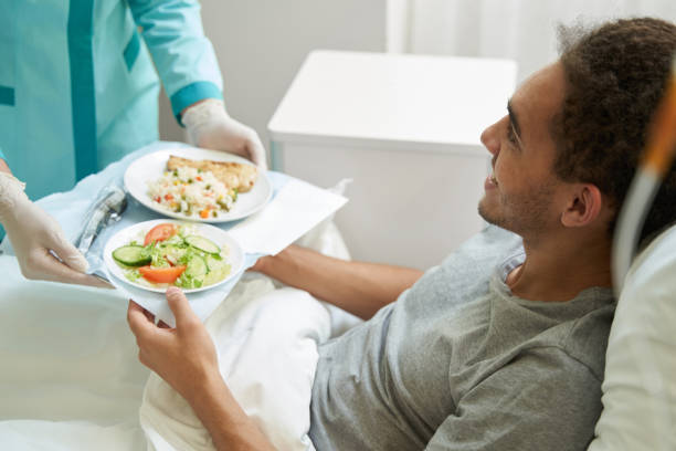 Happy man getting meal on tray from medical center worker stock photo
