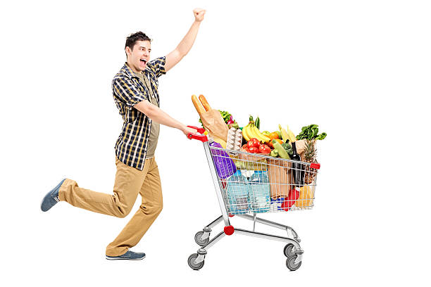 Happy man pushing a shopping cart "Full length portrait of a happy man pushing a shopping cart, isolated on white background" push cart stock pictures, royalty-free photos & images