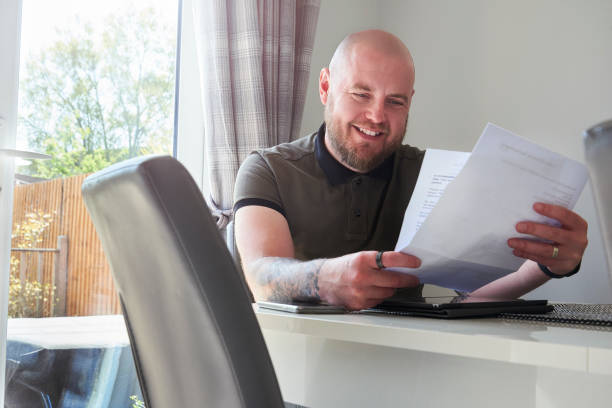 Happy man reading letter at home stock photo