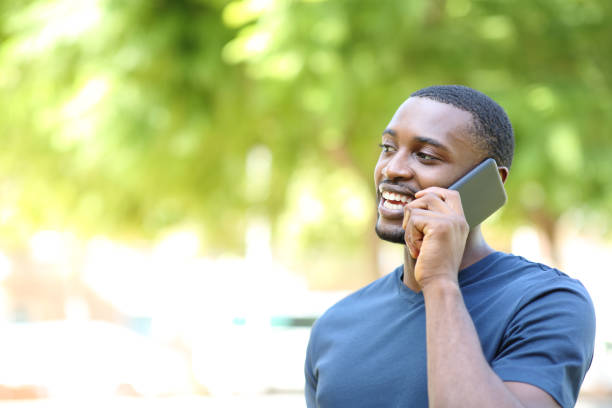 Happy man with black skin talking on phone stock photo