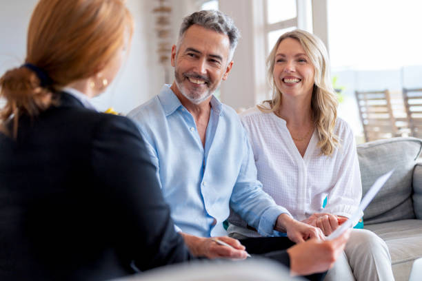 Happy mature couple meeting investments and financial advisor at home. stock photo