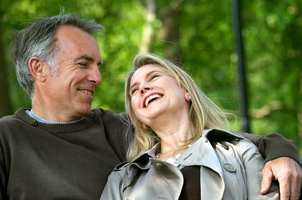 Happy Mature Couple Mature couple aged 50 to 60 sitting on park bench, woman laughing 50 59 years stock pictures, royalty-free photos & images