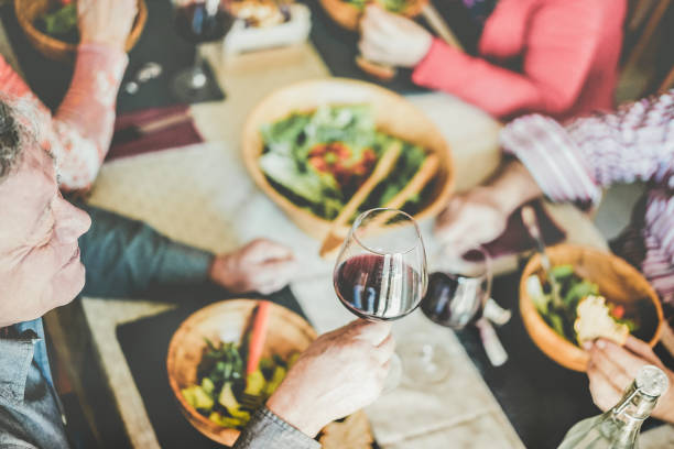 快樂的成熟的人吃在餐廳周日午餐-高級朋友有樂趣吃和喝紅酒-快樂老人的生活方式, 食物和友誼的概念-專注于左男人的鼻子 - england australia 個照片及圖片檔