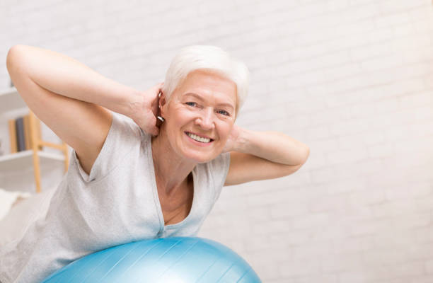 happy mature woman doing exercises with fitness ball - senior gimnastyka zdjęcia i obrazy z banku zdjęć