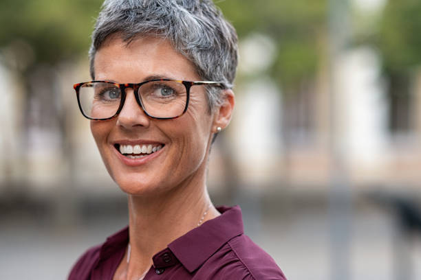 Happy mature woman with spectacles Portrait of mature businesswoman wearing eyeglasses while looking at camera. Smiling middle aged lady with grey short hair wearing spectacles standing outdoor in formal clothing. Close up face of happy successful woman with glasses, copy space. mid adult women stock pictures, royalty-free photos & images