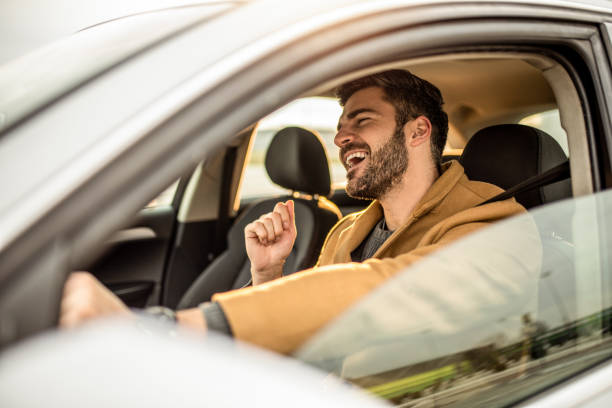 Happy mid adult man driving a car and singing. stock photo