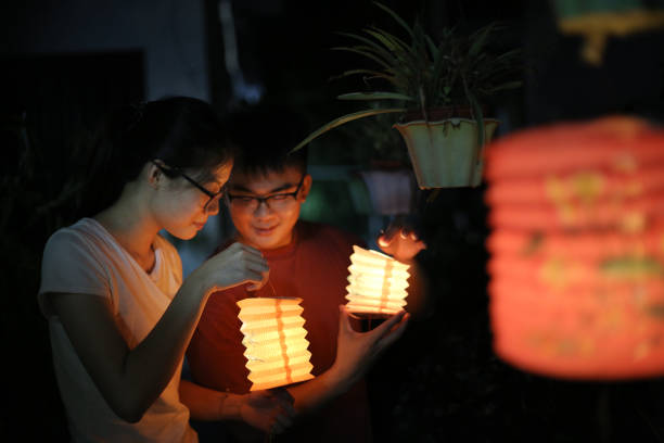 Happy Mid-Autumn Festival! An Asian couple are enjoying decorating garden with lanterns. chinese lantern festival stock pictures, royalty-free photos & images