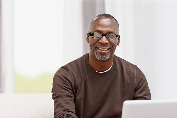 happy middle aged male using latest technology - man jobbar dator ögonkontakt bildbanksfoton och bilder