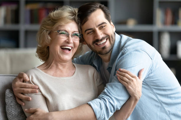 Happy middle aged retired woman watching funny movie with son. stock photo