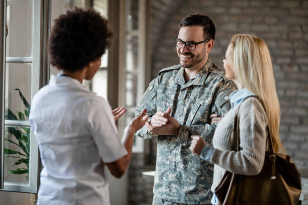 Happy military man and his wife talking to a doctor at medical clinic. Happy army soldier and his wife communicating with African American healthcare worker while having consultations at the clinic. military lifestyle stock pictures, royalty-free photos & images
