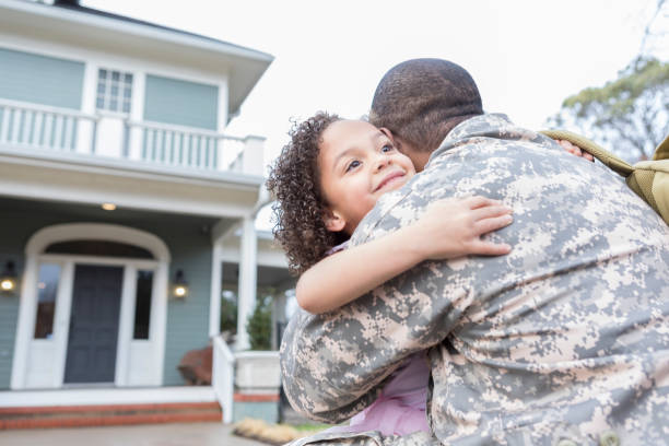 Happy military man greets his daughter after overseas service Excited African American male soldier runs to greet his little girl upon his return home from deployment. His home is in the background. soldiers returning home stock pictures, royalty-free photos & images