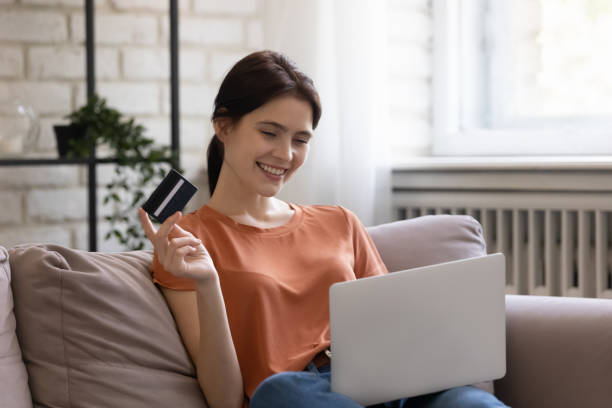Happy millennial woman pay for goods online using credit card stock photo