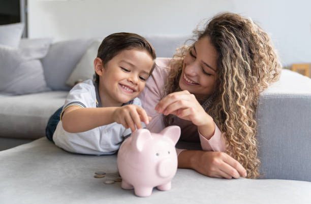 행복 한 어머니와 아들은 돼지 저금통에 돈을 저축 - 저축 뉴스 사진 이미지