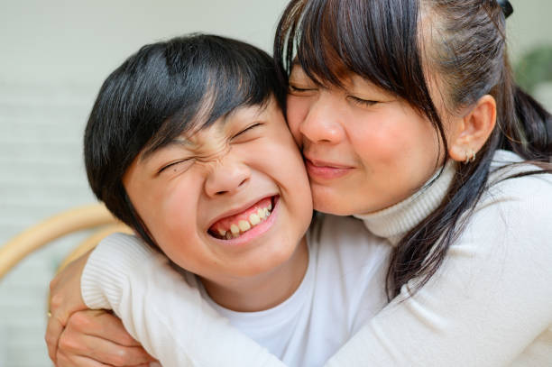 Happy mother embracing and kissing her son stock photo