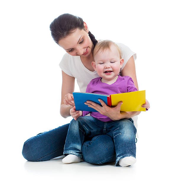 happy mother reading a book to baby girl stock photo