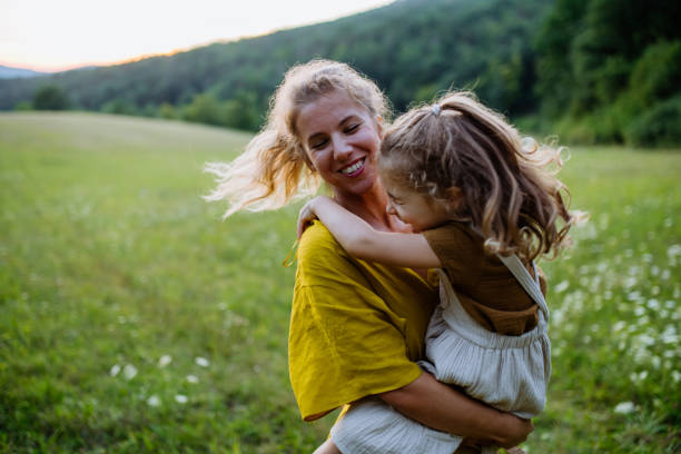 Happy mother spending time with her little daughter outside in green nature. stock photo