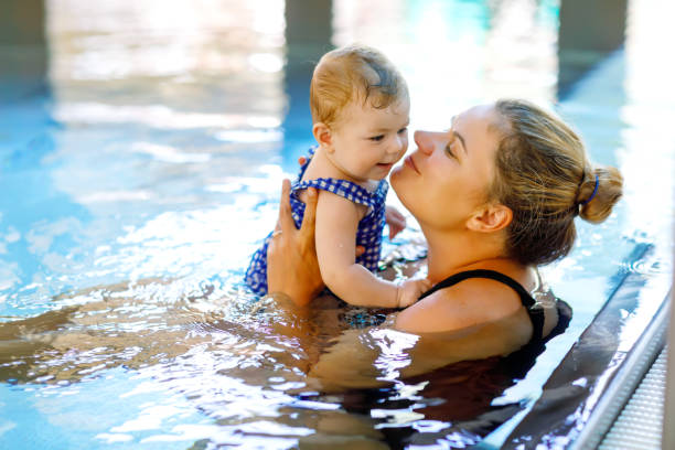 gelukkig moeder zwemmen met schattige schattig baby meisje dochter in zwembad. - swimming baby stockfoto's en -beelden