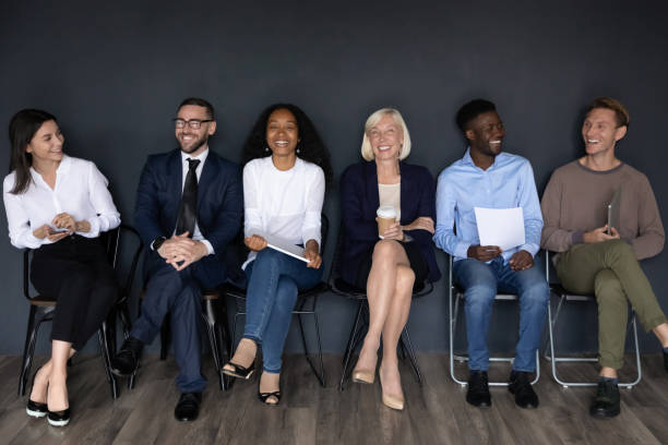 Happy multiracial businesspeople group sit on chairs laughing, human resource Happy multiracial professional business people young and old applicants group sit on chairs laughing having fun wait for job interview sit in row queue, human resource, staffing employment concept candidate stock pictures, royalty-free photos & images
