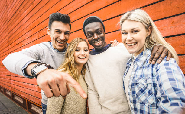 happy multiraciale vrienden groep nemen selfie met mobiele smartphone - jonge hipster mensen die verslaafd door smartphone op sociale netwerk gemeenschap - lifestyle technologie concept op levendig contrast filter - hogeschool rood samen stockfoto's en -beelden