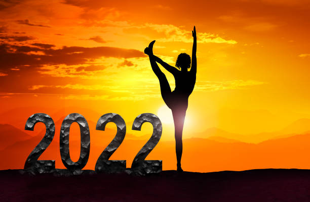 Happy New Year 2022 with woman in yoga pose at sunset stock photo