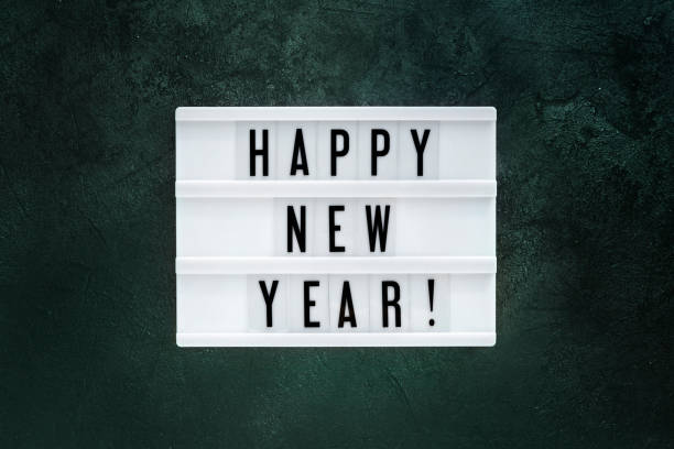 Happy New year displayed on a white vintage lightbox on texture tidewater green background, flat lay on trendy colourful backdrop stock photo