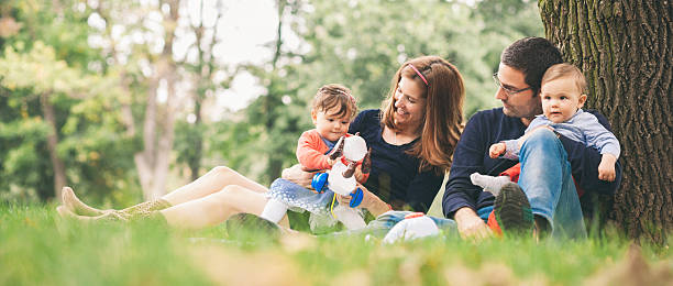 happy parents with kids enjoying spring time in nature - pregnant couple outside stockfoto's en -beelden