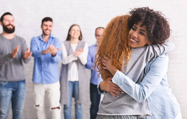 Happy patients embracing during support group session Group therapy meeting. Happy patients embracing during support session, free space drug rehab stock pictures, royalty-free photos & images