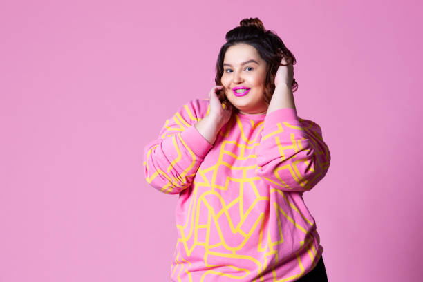 Happy plus size model in casual clothes, fat woman on pink background Happy plus size model in casual clothes, fat woman on pink background, body positive concept beautiful voluptuous women stock pictures, royalty-free photos & images