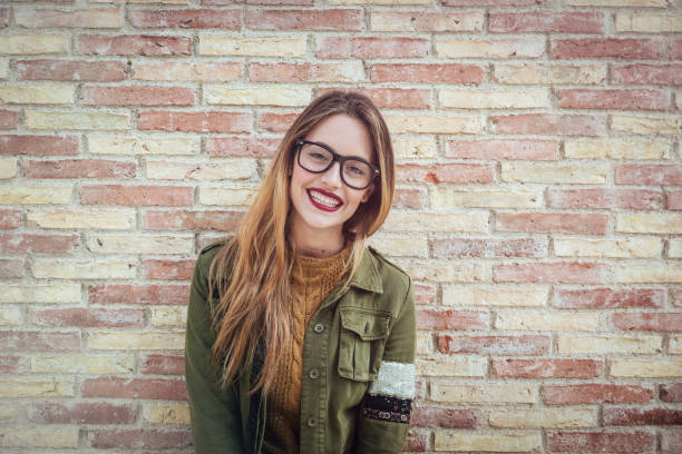 Happy pretty girl standing in front of a brick wall stock photo
