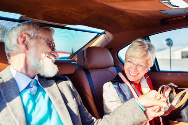 Happy senior adult couple driving in limousine stock photo