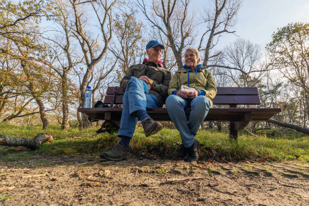 gelukkig hoger paar dat koffie drinkt om op een houten bank te gaan - pensioen nederland stockfoto's en -beelden