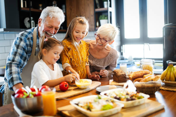 pares sênior feliz que têm o pequeno almoço com seus netos em casa - avós - fotografias e filmes do acervo