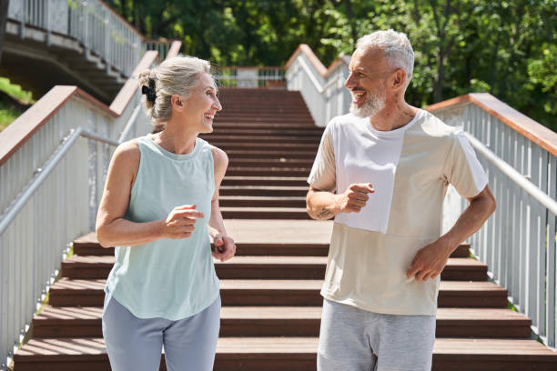 Happy senior couple running with delight at the summer park and trying to keep body fit stock photo