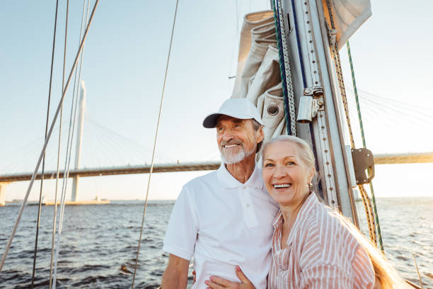 glückliches älteres paar steht am mast. zwei lächelnde menschen genießen bootsfahrt. - segel stock-fotos und bilder
