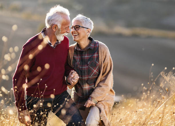 felice coppia senior che parla mentre cammina su una collina nella giornata autunnale. - autunno energia foto e immagini stock