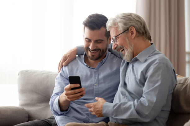 lycklig senior pappa och tusenåriga son använder smartphone tillsammans - far och son bildbanksfoton och bilder