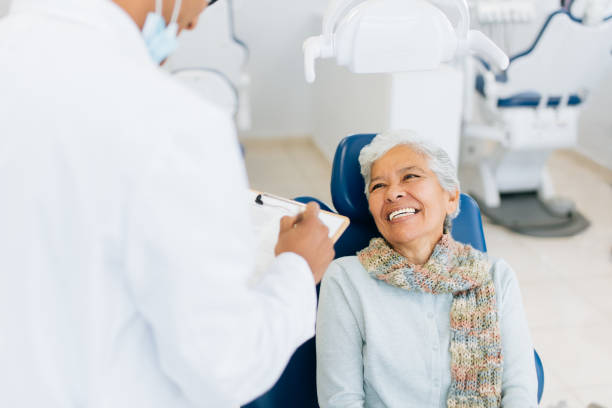 Happy senior patient smiling at male dentist stock photo