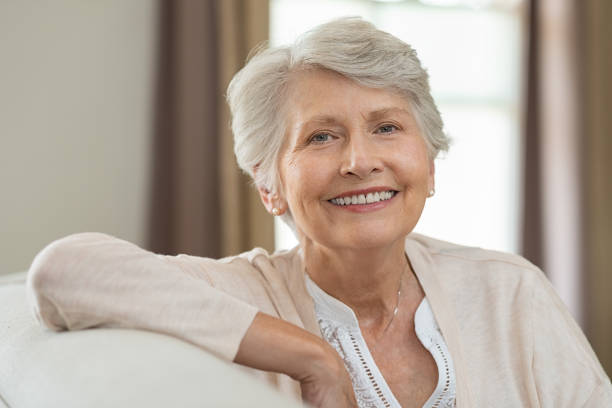 Happy senior woman Smiling senior woman relaxing on couch at home and looking at camera. Portrait of elderly woman sitting on sofa. Closeup of cheerful grandmother relaxing indoor. senior women stock pictures, royalty-free photos & images