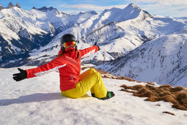 Happy skier girl taking a break above Saint-Jean-d'Arves village, France, in Les Sybelles ski resort. Winter activities. stock photo