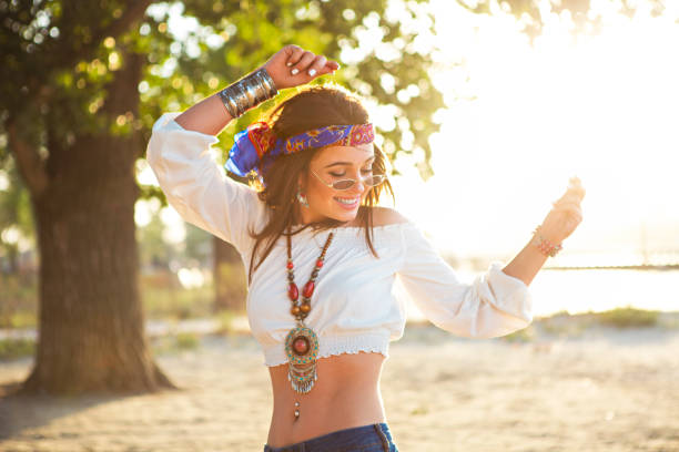 happy slanke tan vrouw in jeans dansen op het strand - festival kleding stockfoto's en -beelden