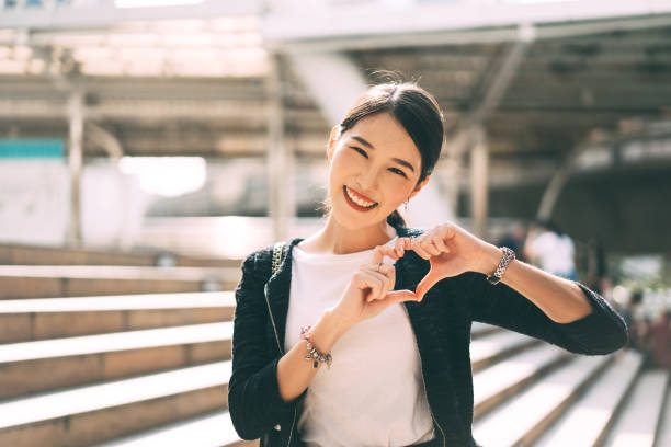Happy smile young adult asian business single woman hand up with heart gesture. stock photo