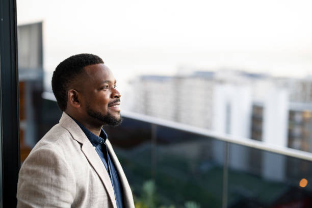 Happy smiling African businessman standing on balcony overlooking the city stock photo