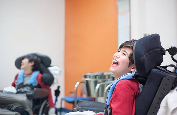 Happy, smiling disabled boy in wheelchair waiting in doctor's office stock photo