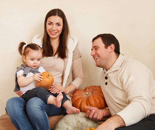bonne famille souriante avec des citrouilles d’automne - father fall studio photos et images de collection