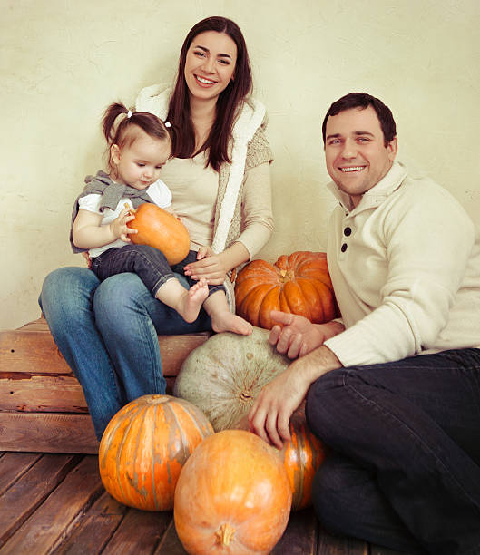 famille souriante heureuse avec une petite fille d’un an à l’intérieur - father fall studio photos et images de collection