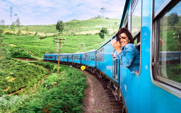 happy smiling woman looks out from window traveling by train on most picturesque train road in sri lanka - happy traveling imagens e fotografias de stock