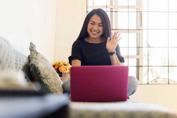 Happy smiling woman sitting on sofa and using laptop Happy smiling woman sitting on sofa and using laptop during video call during coronavirus pandemic. online degrees stock pictures, royalty-free photos & images