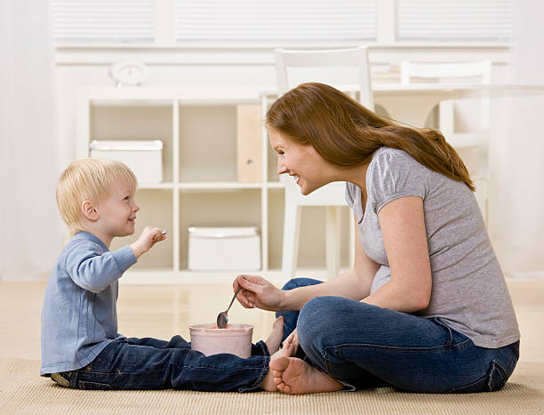 Happy son eats ice cream from tub with excited mother stock photo